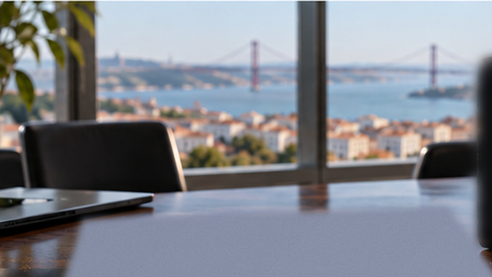 Modern Lisbon boardroom overlooking the Tagus, with a laptop on the conference table.